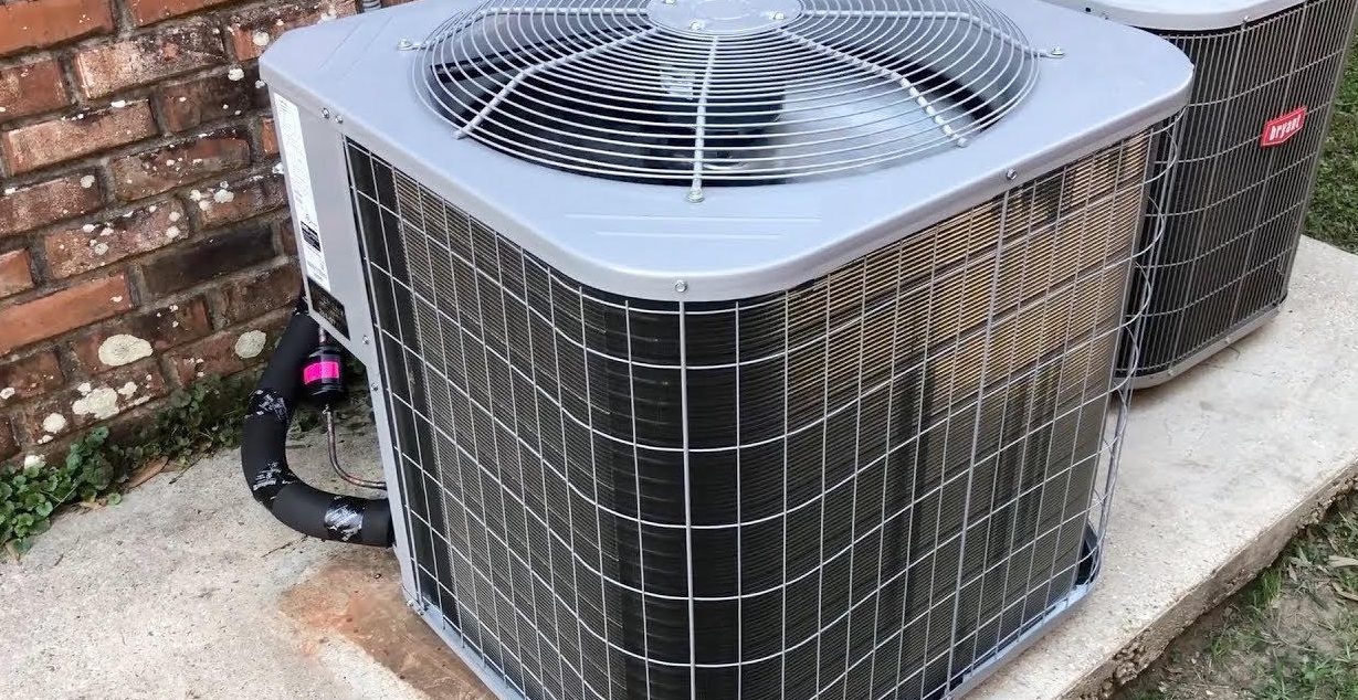 Newly installed outdoor condensers on a pad at a brick home