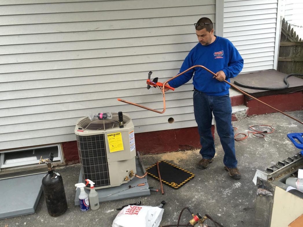 Technician bending a copper lineset at a new outdoor condenser